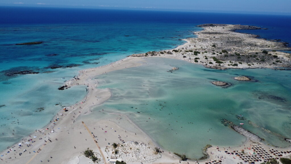 Best Sandy Beaches in Crete  - 1. Elafonissi Beach One of the main reasons why Elafonissi Beach is considered one of the 10 Best Beaches in Crete is its striking pink sand. This unusual phenomenon is caused by the combination of crushed coral and seashells mixed with the fine, white sand. The pink hue is most noticeable during the sunny hours of the day when the sunlight reflects off the sand, creating a soft, almost surreal effect. As you walk along the shoreline, the sand seems to shimmer with varying shades of pink, creating a truly magical experience.