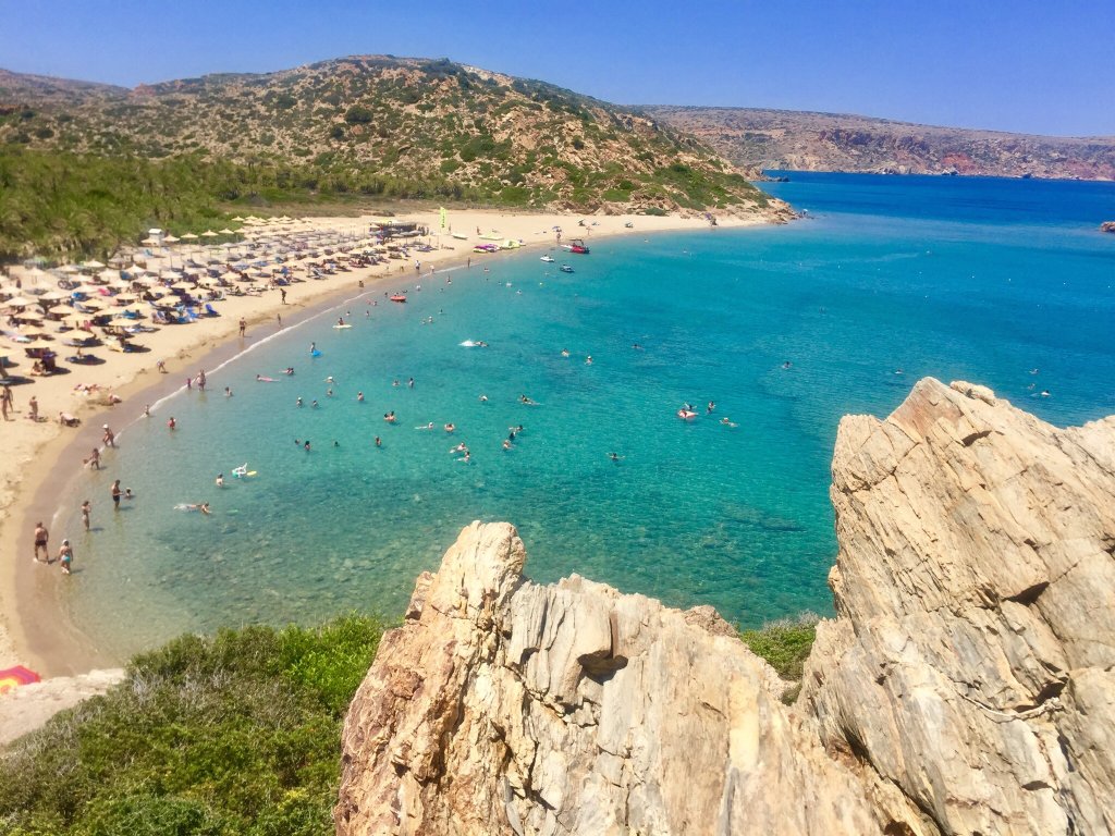 "Best Sandy Beaches in Crete" - 3. Vai Beach. Vai Beach: The Palm Beach of Crete
Located in the far eastern part of Crete, Vai Beach is one of the island’s most unique and captivating destinations. This beach stands out not only for its stunning turquoise waters and golden sand but also for its special feature: the largest natural palm forest in Europe. The combination of palm trees, clear blue waters, and the beautiful sandy shoreline gives Vai a distinctive tropical feel that is unmatched on the island. Whether you’re looking for relaxation or adventure, Vai Beach offers a slice of paradise that makes it a must-visit location on Crete.

H4: Why Vai Beach is Famous for Its Unique Palm Forest
Vai Beach is truly one of a kind, mainly because of its remarkable palm forest. This lush grove of Cretan Date Palms (Phoenix theophrasti) is a rare sight in Europe and is one of the last remaining palm forests in the Mediterranean region. The palm trees cover the entire area near the beach, providing natural shade for visitors and creating a picture-perfect landscape that feels almost like a tropical island.

This palm forest is protected, and access to certain areas is restricted to preserve the delicate ecosystem. The combination of golden sand, clear turquoise water, and the unique palm trees creates a beautiful contrast, making Vai Beach an iconic spot for both relaxation and photography. The sight of the palm forest stretching toward the sea is something that stays in the memory long after leaving the beach.